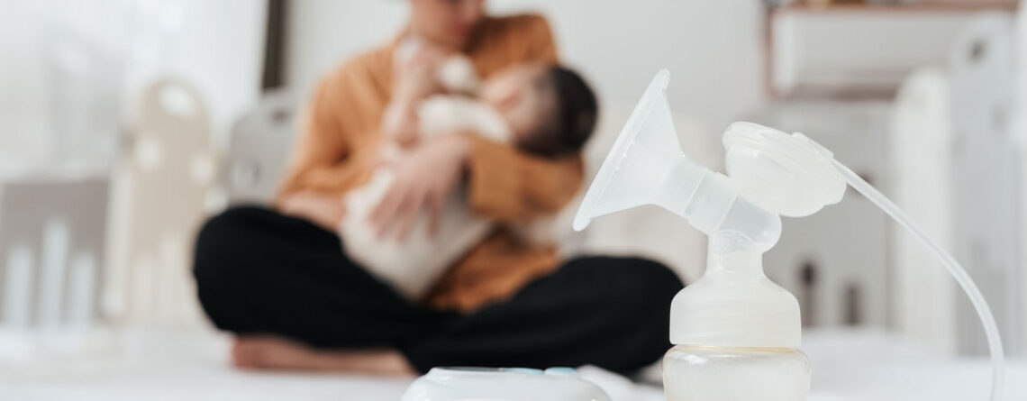 Breast pump on bed in front of mom and baby