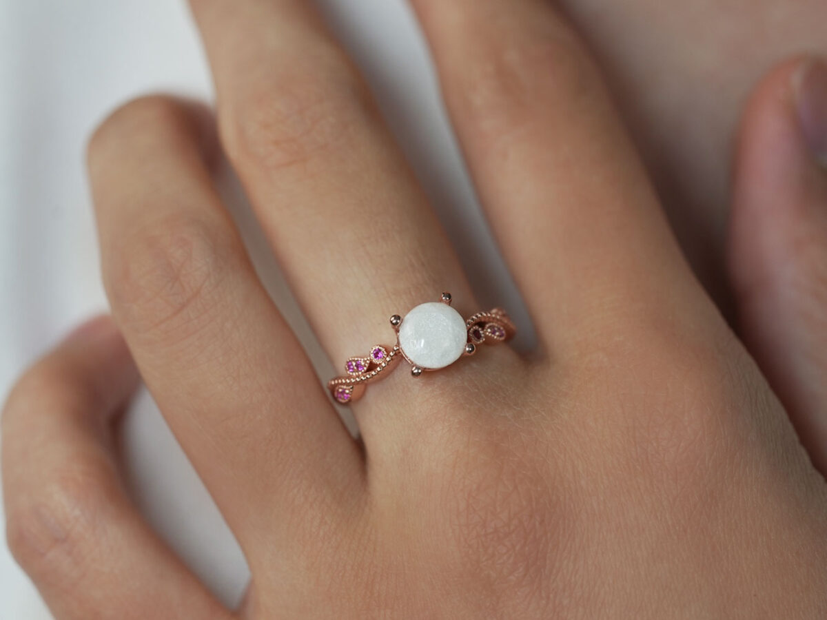 breastmilk jewelry ring on a model hand close-up in rose gold round pink stones