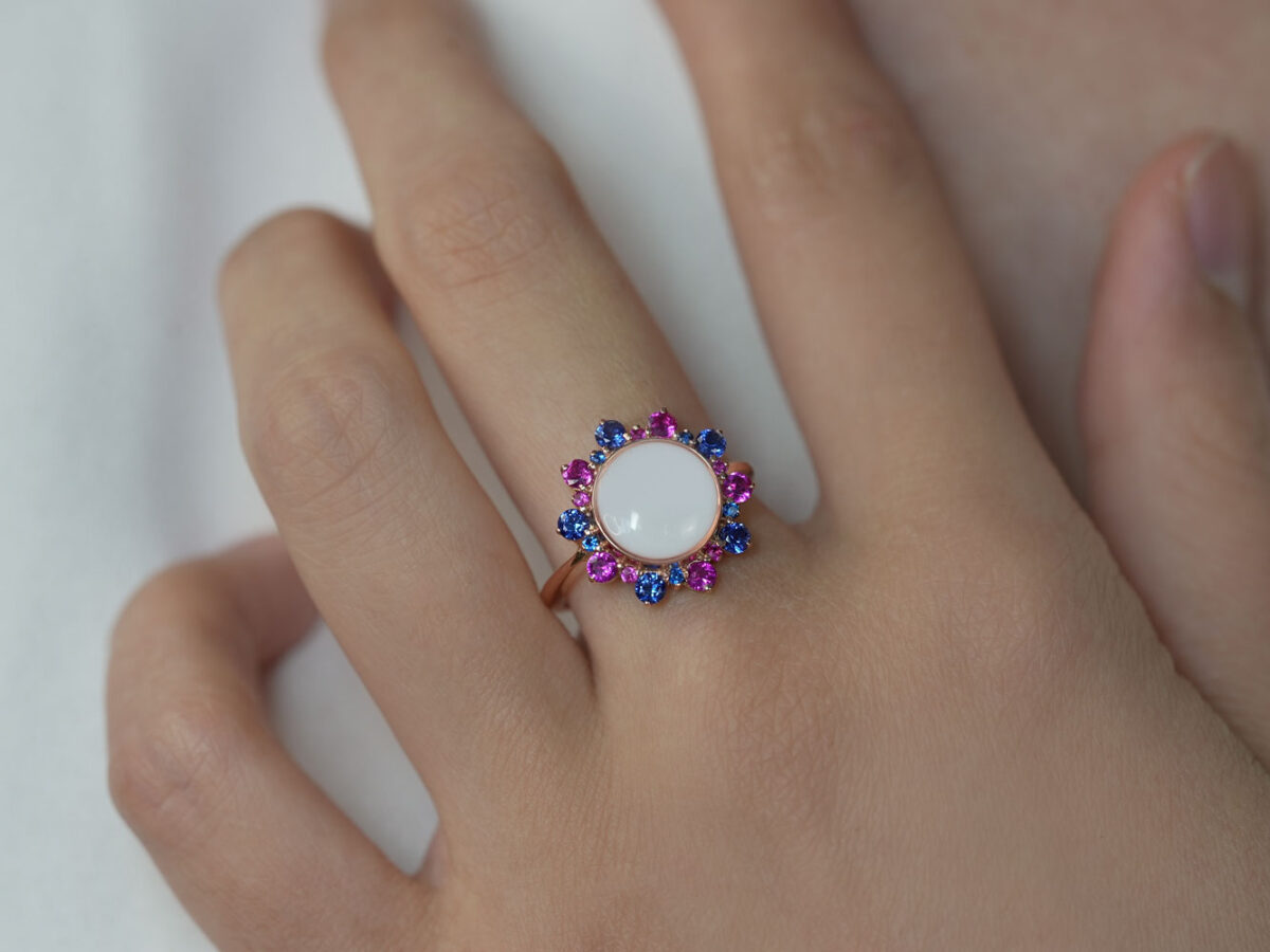 breastmilk jewelry ring on a model hand close-up in rose gold round flower hot pink and deep blue halo crystals