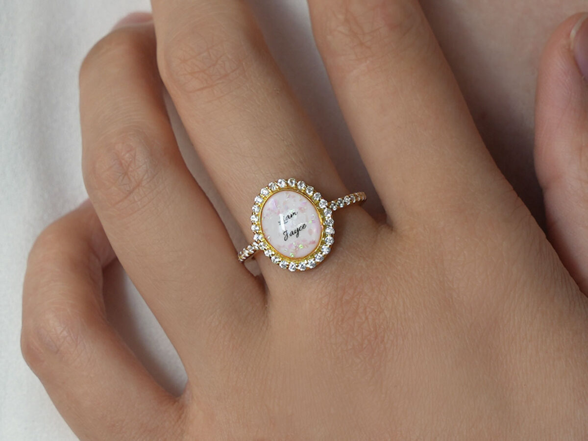 breastmilk jewelry ring on a model hand close-up in gold oval halo clear crystals and name