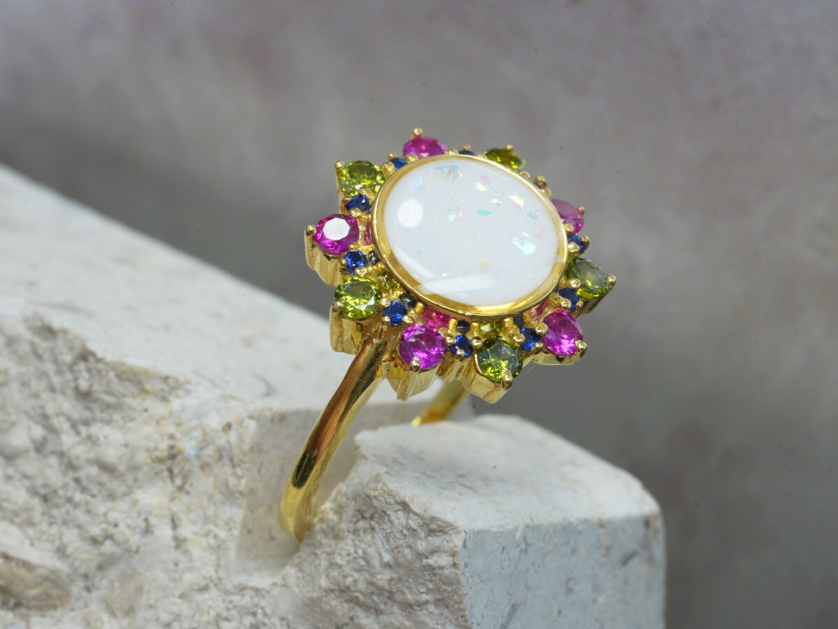 breastmilk ring flower shape with large center breastmilk round stone crystals halo with ruby red and sapphire blue birth month color gems from keepsakemom rose gold plated over sterling silver with round central breastmilk stone side view