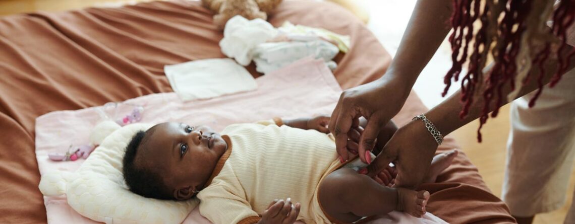 Mother changing newborn baby’s diaper