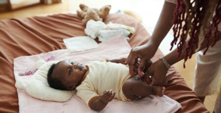 Mother changing newborn baby’s diaper