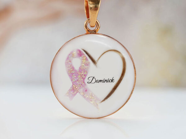 breastmilk necklace disc with heart made with baby's hair and pink gems with golden shimmer ribbon breastmilk cancer awareness with baby's name inside from keepsakemom