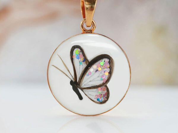 breastmilk jewelry disc necklace filled with breastmilk and outline of butterfly made with baby's hair with multicolored shimmer wings from keepsakemom