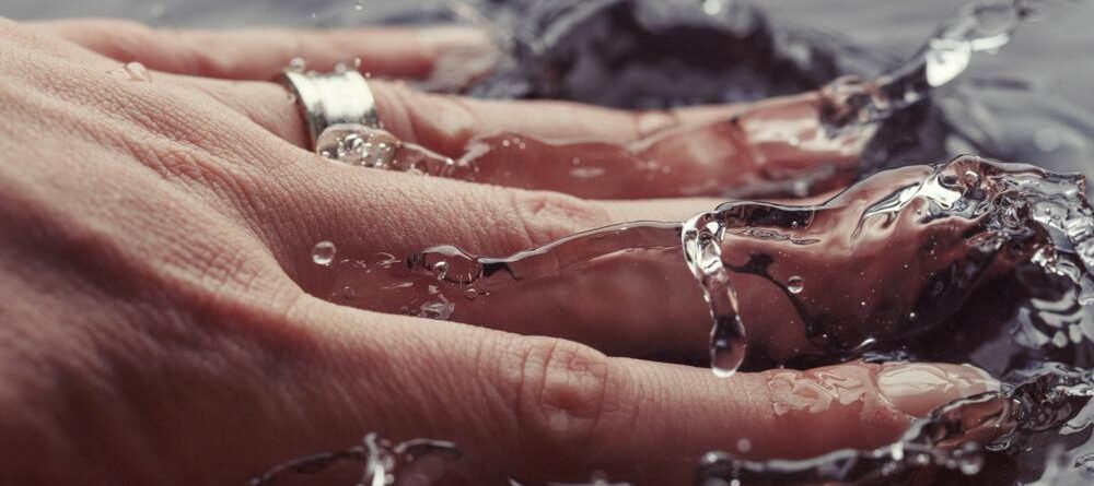 Woman’s hand with ring splashing water