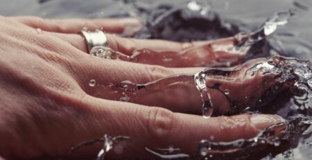 Woman’s hand with ring splashing water
