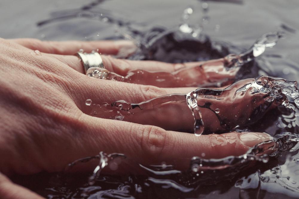 Woman’s hand with ring splashing water