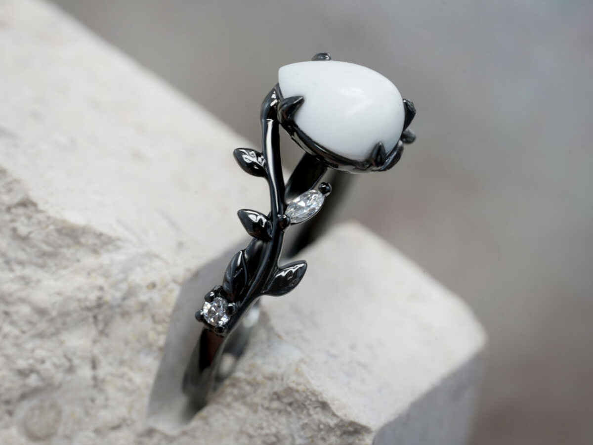 breastmilk ring in rare black setting rhodium or black gold with central breast milk stone in shape of domed drop and clear diamonds birth month color gems and stones on a band from keepsakemom