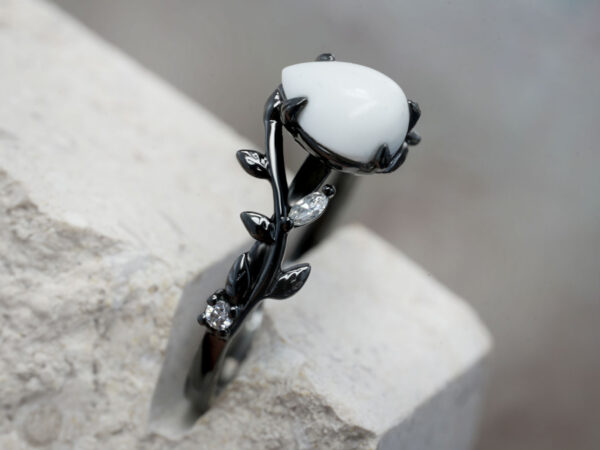 breastmilk ring in rare black setting rhodium or black gold with central breast milk stone in shape of domed drop and clear diamonds birth month color gems and stones on a band from keepsakemom