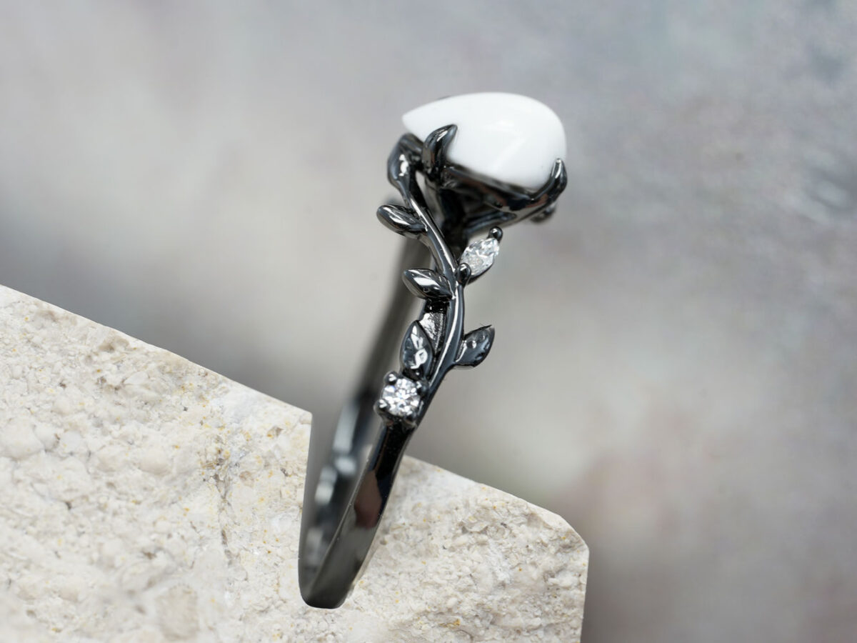 breastmilk ring in rare black setting rhodium or black gold with central breast milk stone in shape of domed drop and clear diamonds birth month color gems and stones on a band from keepsakemom