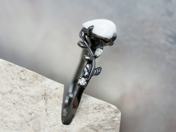 breastmilk ring in rare black setting rhodium or black gold with central breast milk stone in shape of domed drop and clear diamonds birth month color gems and stones on a band from keepsakemom