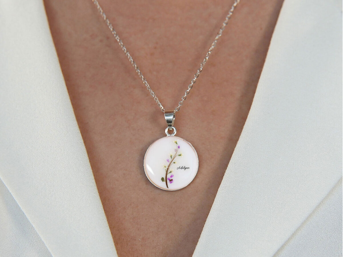 breast milk necklace disc with tree of life made with baby's hair forming a branch and real flowers on model chest
