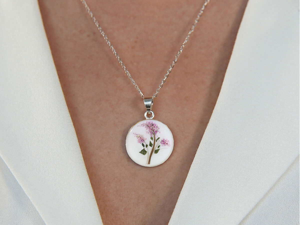breast milk necklace disc made with baby's hair and filled with purple gems forming lilac flowers on model chest