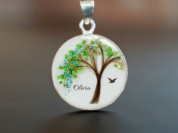 Hair jewelry round disc necklace with tree of life made with hair green leaves in flakes and turquoise gems with baby lock of hair as tree trunk and bird and name olivia from Keepsakemom