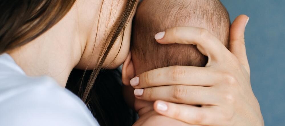 A new mother cradles her baby’s head while bonding after a feeding.
