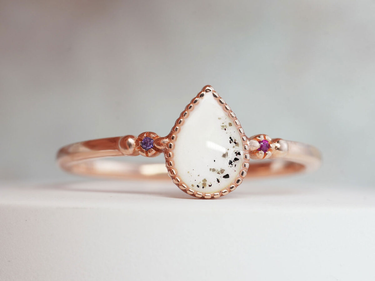 memorial ring breastmilk jewelry with memorial ashes filled in teardrop shaped ring with two colored crystals purple and pink in rose gold from keepsakemom