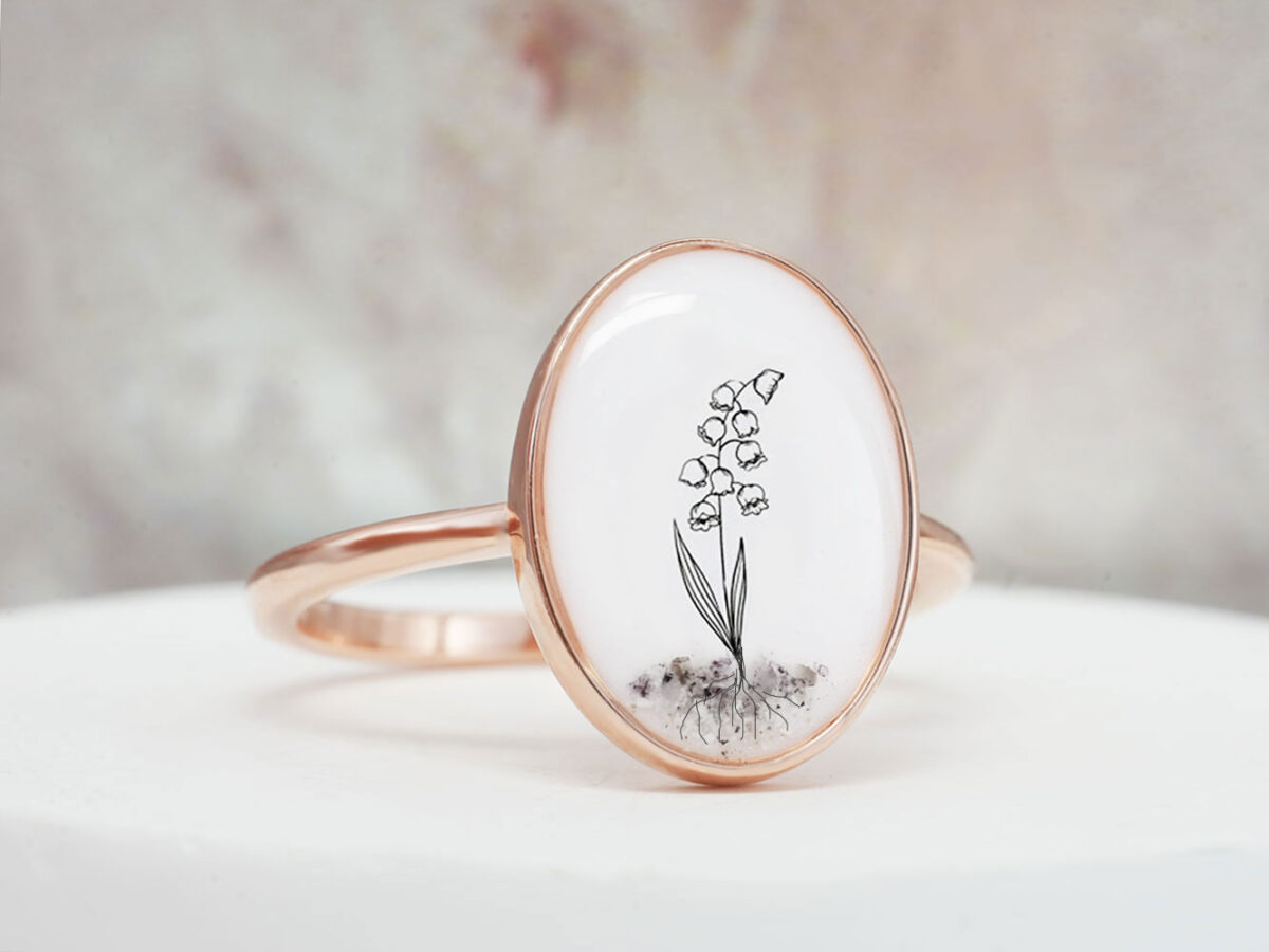 keepsake remembrance memorial ring in oval shape filled with breastmilk and flower with ashes at the bottom in rose gold setting from keepsakemom