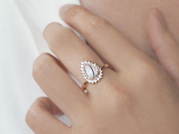 memorial cremation ring with ashes on a model hand, adorned with clear crystals in rose gold filled with breastmilk and ashes and lock of hair from keepsakemom