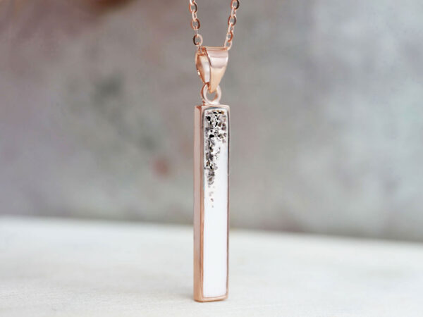 memorial keepsake jewelry bar necklace filled with breastmilk and ashes sprinkled on top in rose gold setting with light background from keepsakemom