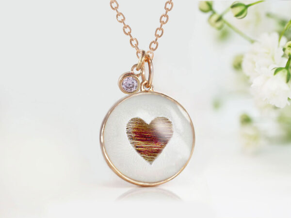 memorial jewelry, a necklace for a cat owner with a heart shaped from the cat's fur in a disc on white background, a small rose gold pendant on a gold chain from keepsakemom