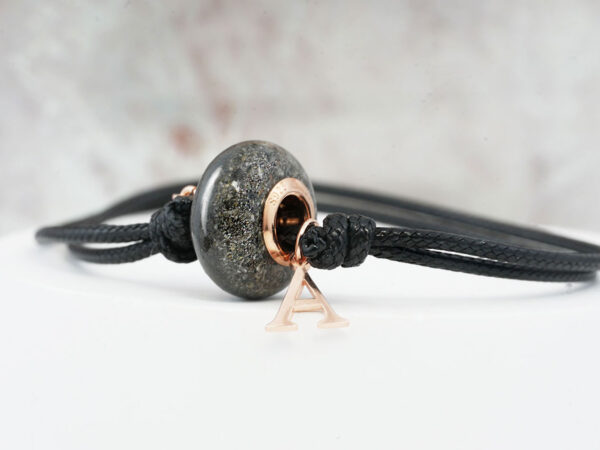 memorial jewelry, a smooth round bead made from animal's ashes for a pet owner, a bead has rose gold cores and is on a black cord with pet's initial as a rose gold charm from keepsakemom