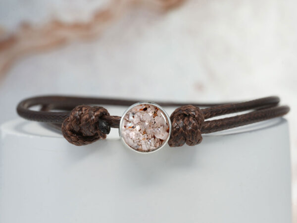 memorial jewelry, a bracelet disc filled with dog's ashes on a brown cord for a pet owner from keepsakemom