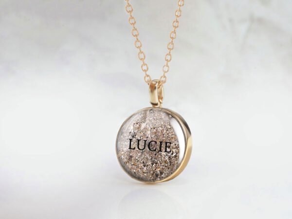 memorial jewelry, a necklace for a pet owner with animal's ashes and the name of a pet printed on the stone, a small round yellow gold disc on a gold chain from keepsakemom