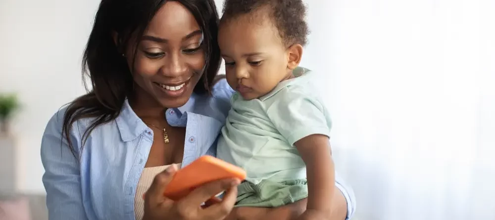A happy mother and baby looking at a phone.